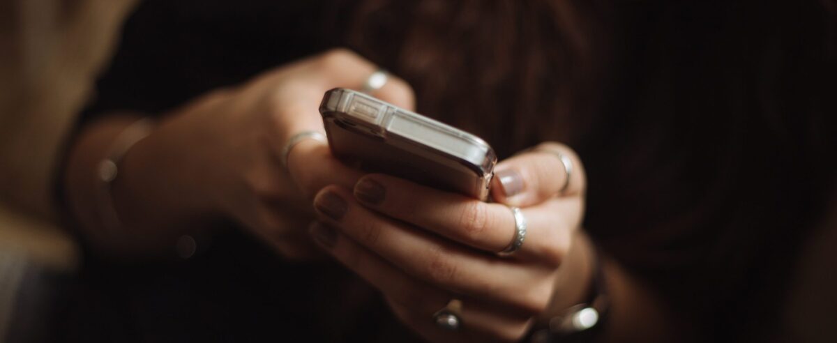 woman wearing lots of rings texting on a phone