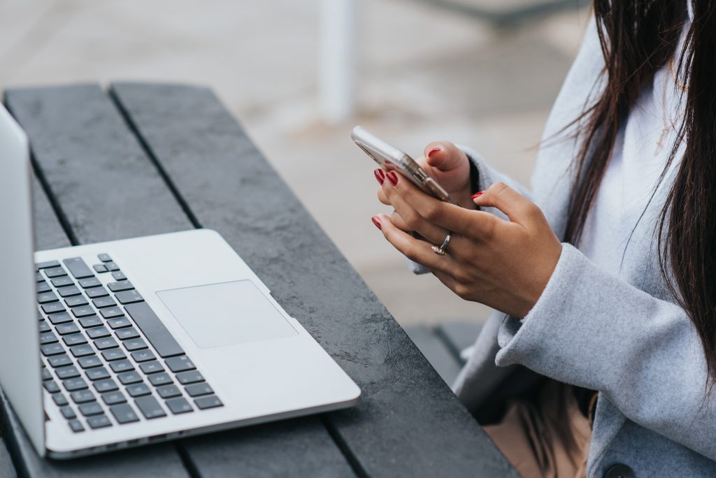 Girl sitting in front of laptop using cell phone