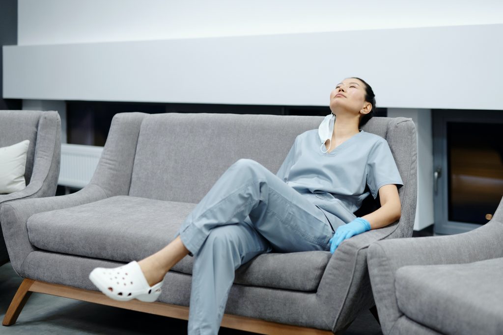 Nurse in gray scrubs sitting on couch