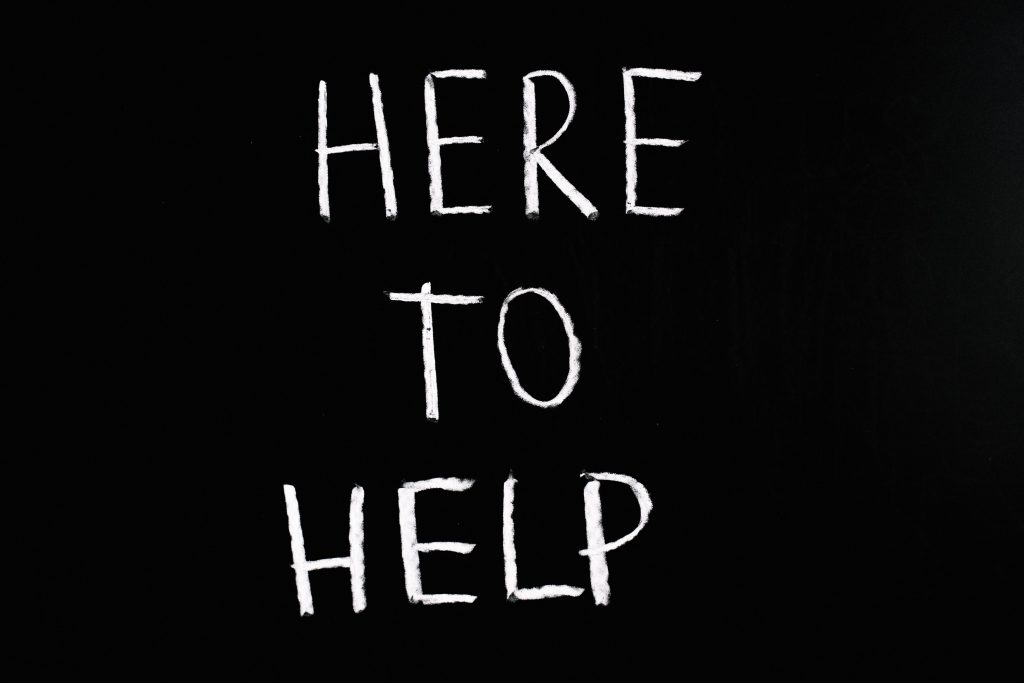 Black and white sign saying "here to help"